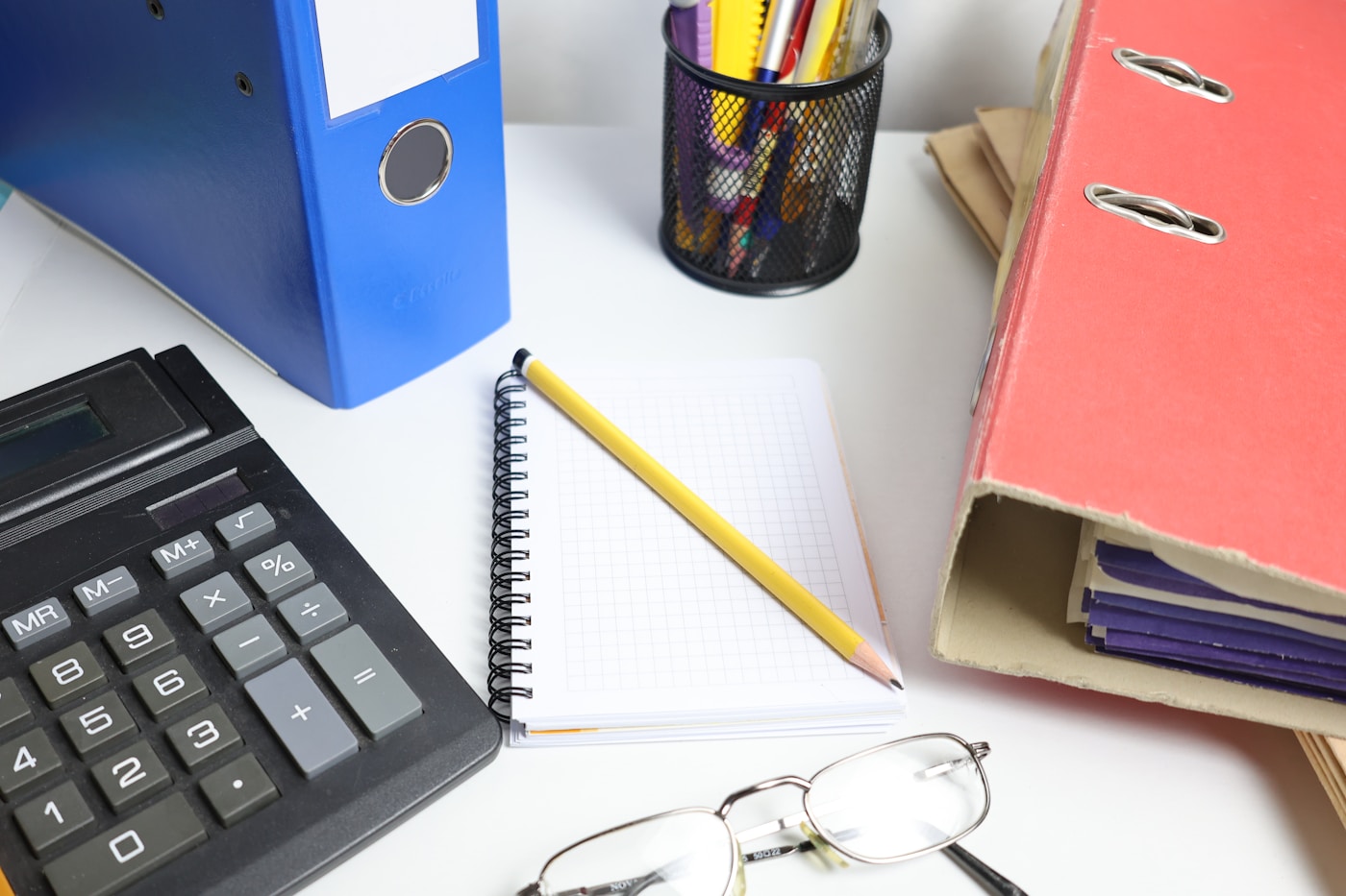 Clean accounting desk with calculator, binders, notebook and glasses